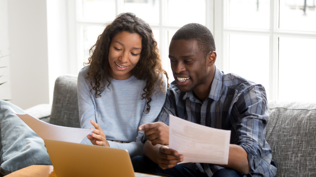 Smiling couple looking at paperwork and laptop