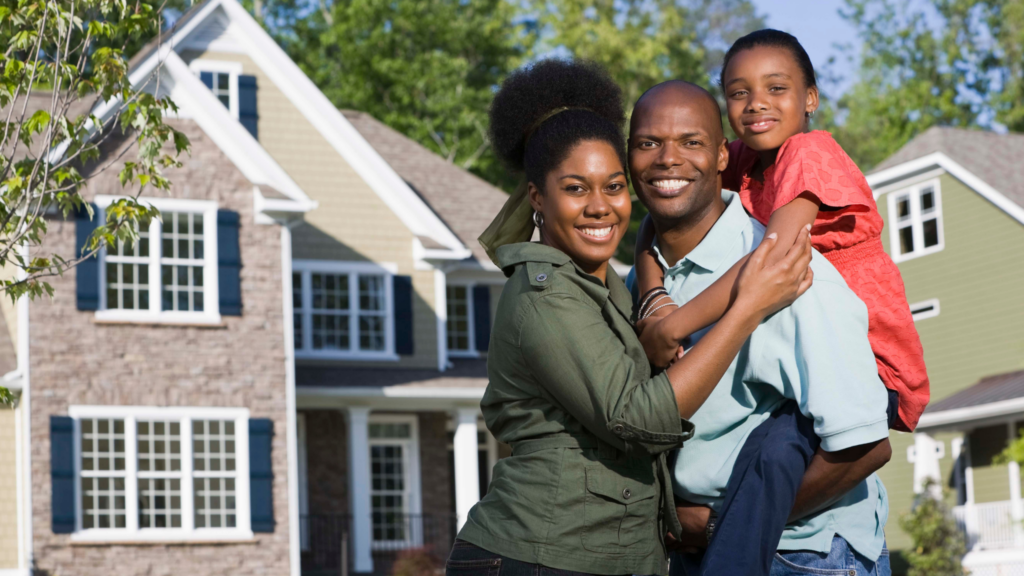 African American family smiling in front of house