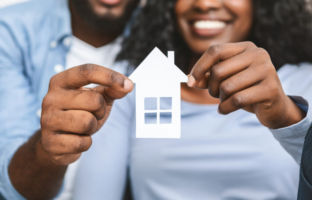 African American couple holding a paper cutout of a house